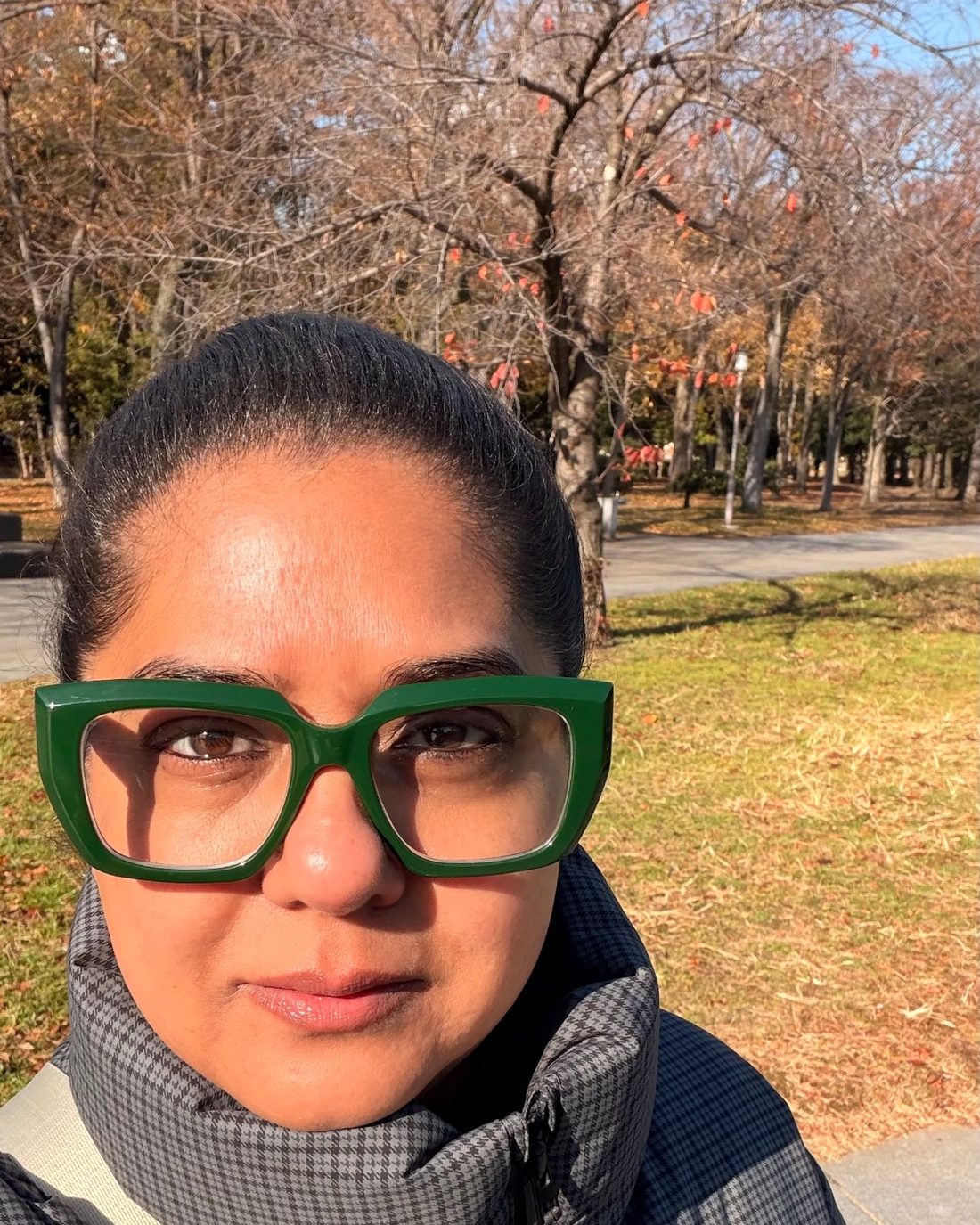 Kavea in green glasses and a houndstooth jacket in an autumn park