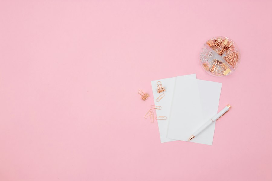 Notepad, pen and clips on a pink desk