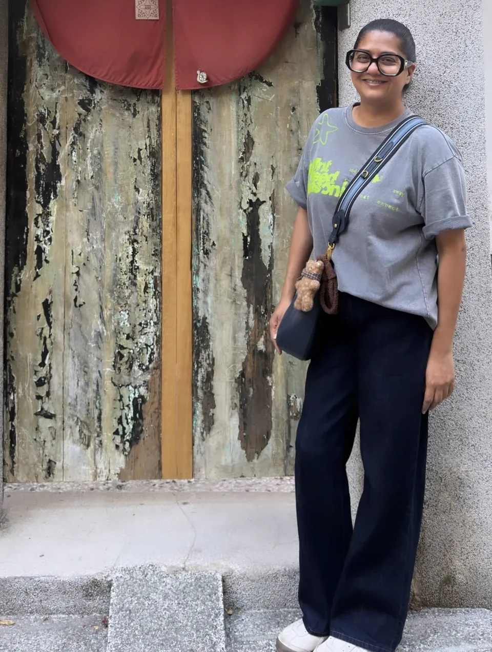 Kavea standing by a weathered wooden door
