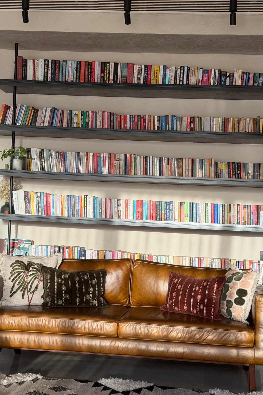 Kavea's home library with books and a leather sofa
